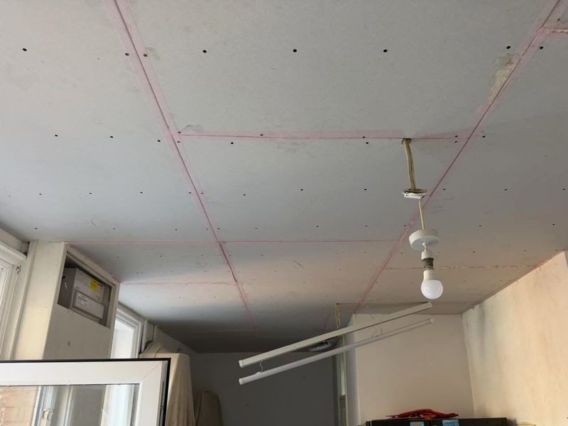 The kitchen ceiling over-boarded with new plasterboard, pink tape on every joint
